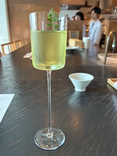 Wine glass with iced green tea and a small sprig of pepperment
