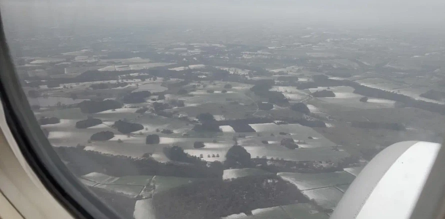 A picture taken from inside a commercial flight looking out through the window.