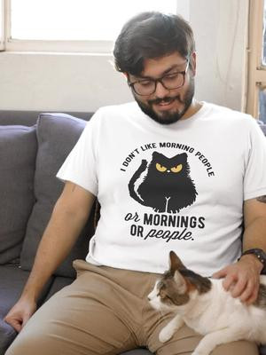 Anti-Morning Cat Tee Express your disdain for mornings and people alike with our 'Anti-Morning Cat' tee. Featuring an angry-looking black cat with piercing yellow eyes, this shirt captures the essence of not being a morning person. The bold text 'I don't like morning people. or mornings. or people' perfectly encapsulates the sentiment of anyone who struggles to function before their first cup of coffee. Made from 100% cotton with a slightly relaxed fit, this tee is as comfortable as it is relatable. Ideal for cat lovers, night owls, or anyone with a healthy dose of sarcasm. Wear it proudly to make your stance clear: mornings are overrated. Hashtags: #AntiMorningCat  #NotAMorningPerson  #CatLovers  #NightOwls  #SarcasticTee  #FunnyShirt  #QuirkyApparel  #CatsOverMornings  #MorningHaters  #SleepLate  #NoMornings  #NoPeople  #CottonTee  #RelaxedFit  #GildanTee  #HumorousApparel  #CatGraphicTee  #AngryCat  #SarcasticFashion  #ComfortableTee  #FunnyFashion  #CatEyes  #MorningStruggles  #NoCoffeeNoTalkie  #MorningBlues #tshirt #tshirs #tshirtshop #thewolfandthebutterfly
