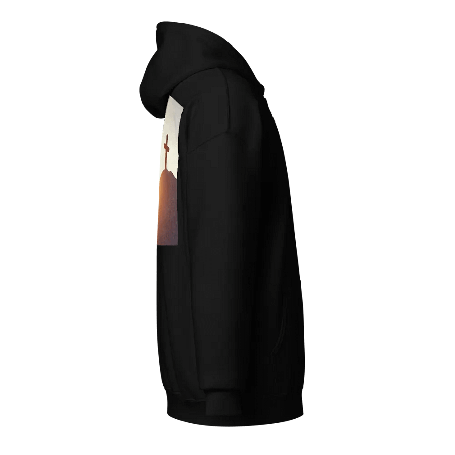 A cross placed on top of a rocky hill, bathed in the warm glow of a sunrise or sunset Hoodie product image (4)