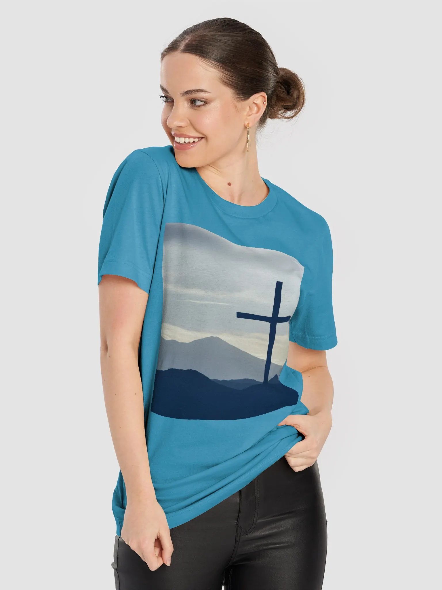 A cross standing against a serene landscape of rolling hills and distant mountains under a soft, cloudy sky t-shirt product image (3)