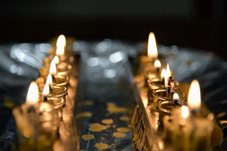 Two rows of lit candles. Photo by @sfkopstein at Unsplash.