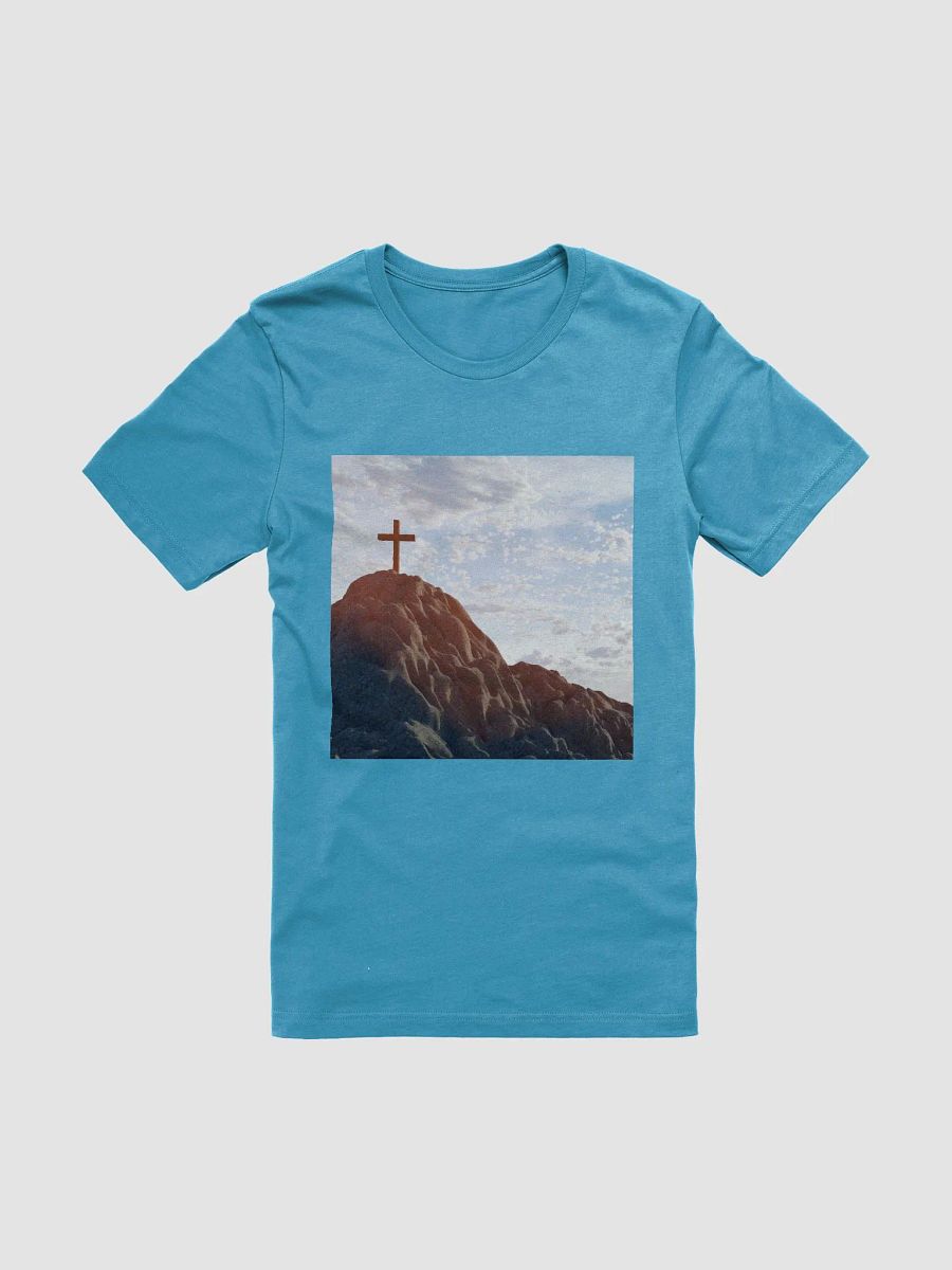 Wooden cross standing atop a rocky hill or mountain, under a sky filled with soft clouds and warm sunlight t-shirt product image (1)