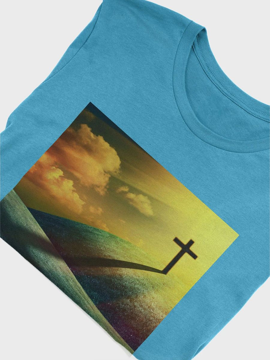 A cross standing prominently on a grassy hill, with a vivid, dramatic background t-shirt product image (7)