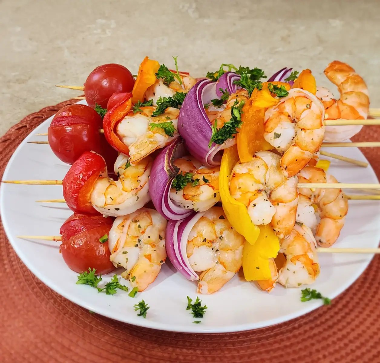 Ingredientes  * 450 gramos de camarones grandes, pelados y desvenados (frescos o descongelados)  * 1 pimiento rojo, cortado en trozos de 2-3 cm  * 1 pimiento amarillo,o verde, naranja al gusto, cortado en trozos de 2-3 cm * 1 Cebolla morada cortada en trozos  * 9 Tomate Cherry    * 1/4 taza de aceite de oliva virgen extra  * Jugo de 1 limón (aproximadamente 2-3 cucharadas)  * 2 dientes de ajo, picados finamente  * 1 cucharada de orégano seco  * Sal y pimienta negra al gusto  * Brochetas de madera o metal (si usas de madera, remójalas en agua por al menos 30 minutos) Instrucciones  * Prepara el adobo: En un bol mediano, combina el aceite de oliva, el ajo picado, el jugo de limón, el orégano, la sal y la pimienta. Mezcla bien todos estos ingredientes aromáticos.  * Adoba los camarones y pimientos: Agrega los camarones pelados y los trozos de pimiento al adobo. Mezcla con suavidad para asegurarte de que tanto los camarones como los pimientos queden bien cubiertos. Deja marinar por unos 15-20 minutos a temperatura ambiente. Esto es suficiente para que absorban los sabores sin que el limón 
