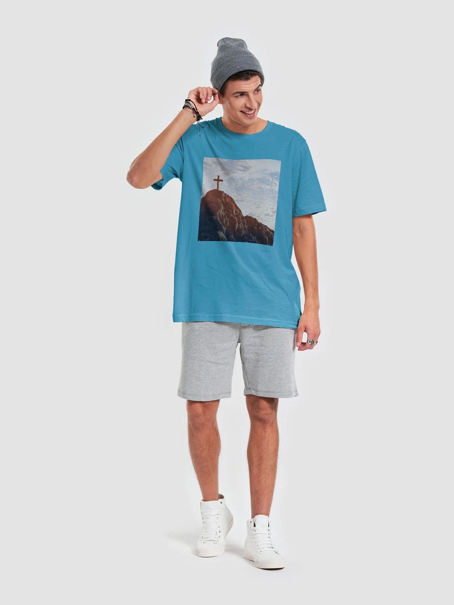 Wooden cross standing atop a rocky hill or mountain, under a sky filled with soft clouds and warm sunlight t-shirt product image (8)