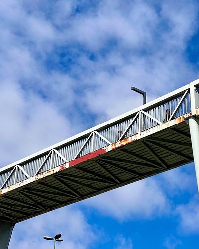 A minimalist perspective of an urban pedestrian bridge against the backdrop of a vivid blue sky. Simplicity meets functionali...