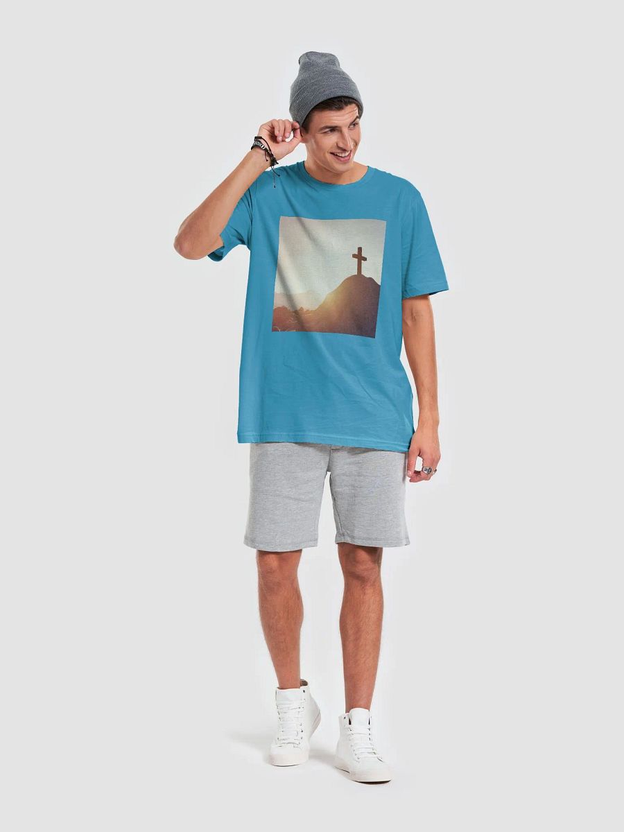 A cross placed on top of a rocky hill, bathed in the warm glow of a sunrise or sunset t-shirt product image (3)