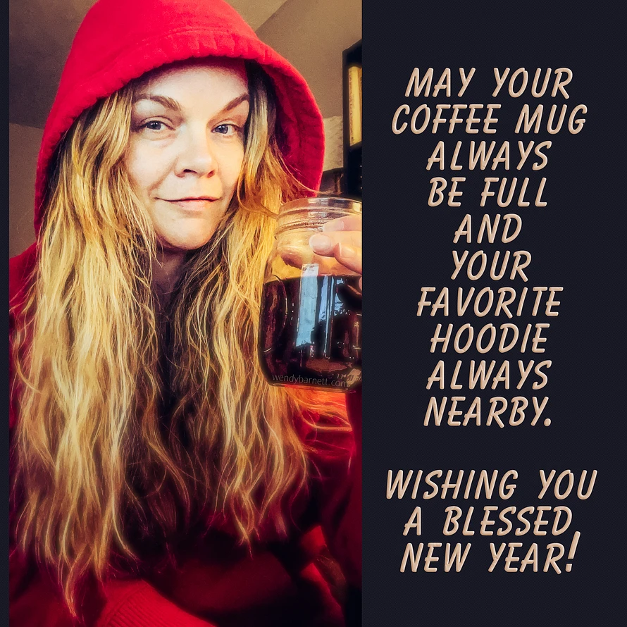 Blonde woman smiles at camera, holding cup of coffee up as in a cheers motion. 