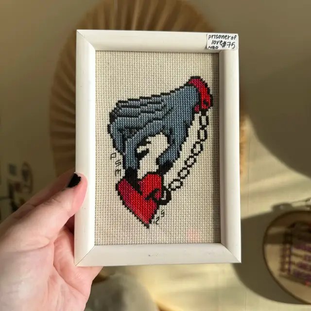 a small collection of my stitches that are in frames! first a mini prisoner of love, the sources i can find attribute to this design to don ed hardy, a true master of the craft and taught from the best. second is a bright blue rose in a chunky trad style. i always end up wanting to make blue roses, a la twin peaks. i really love how it fits in a square frame. third is a gentlemanly devil portrait, in a charming little brass frame that i thrifted from the op shop around the corner! i love metal frames so much, they have so much character. last, a photo of me from my birthday last month 🖤  #crossstitch #fiberart #crossstitchoftiktok #tattooflash #maker 