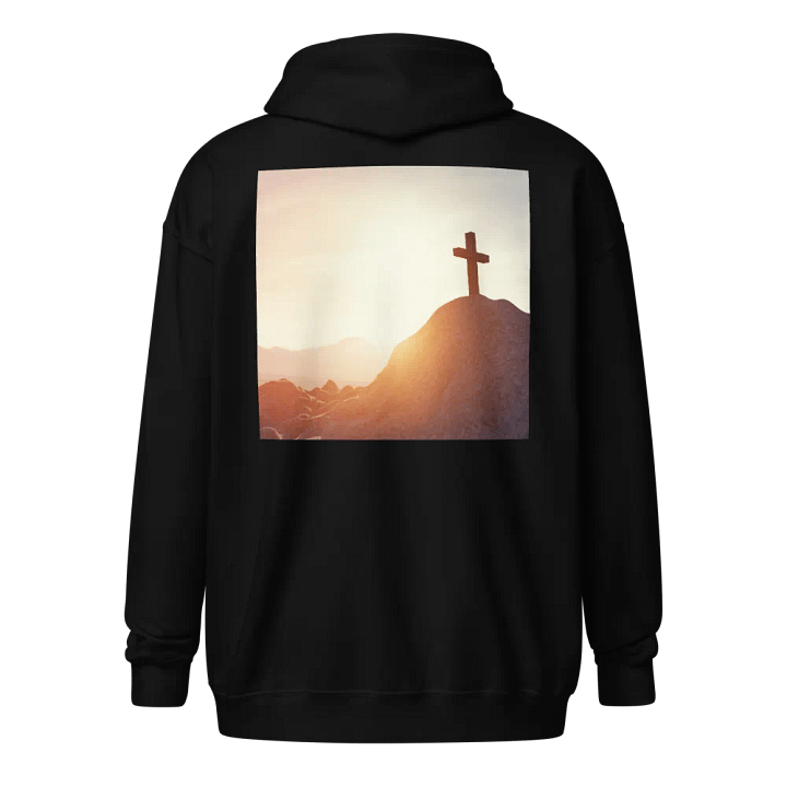 A cross placed on top of a rocky hill, bathed in the warm glow of a sunrise or sunset Hoodie product image (1)