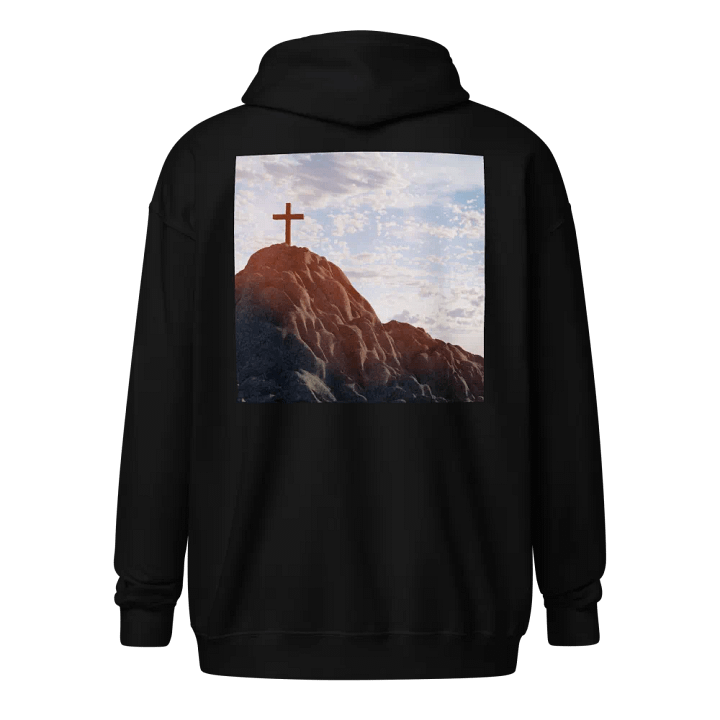 Wooden cross standing atop a rocky hill or mountain, under a sky filled with soft clouds and warm sunlight Hoodie product image (1)