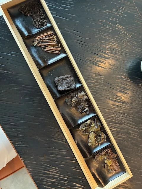 Five samples of tea leaves in a tray.
