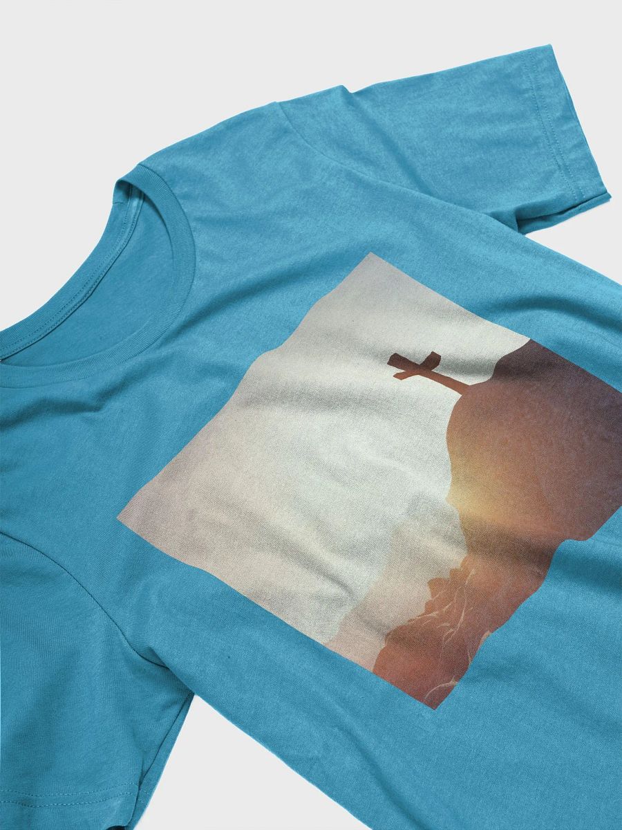 A cross placed on top of a rocky hill, bathed in the warm glow of a sunrise or sunset t-shirt product image (7)