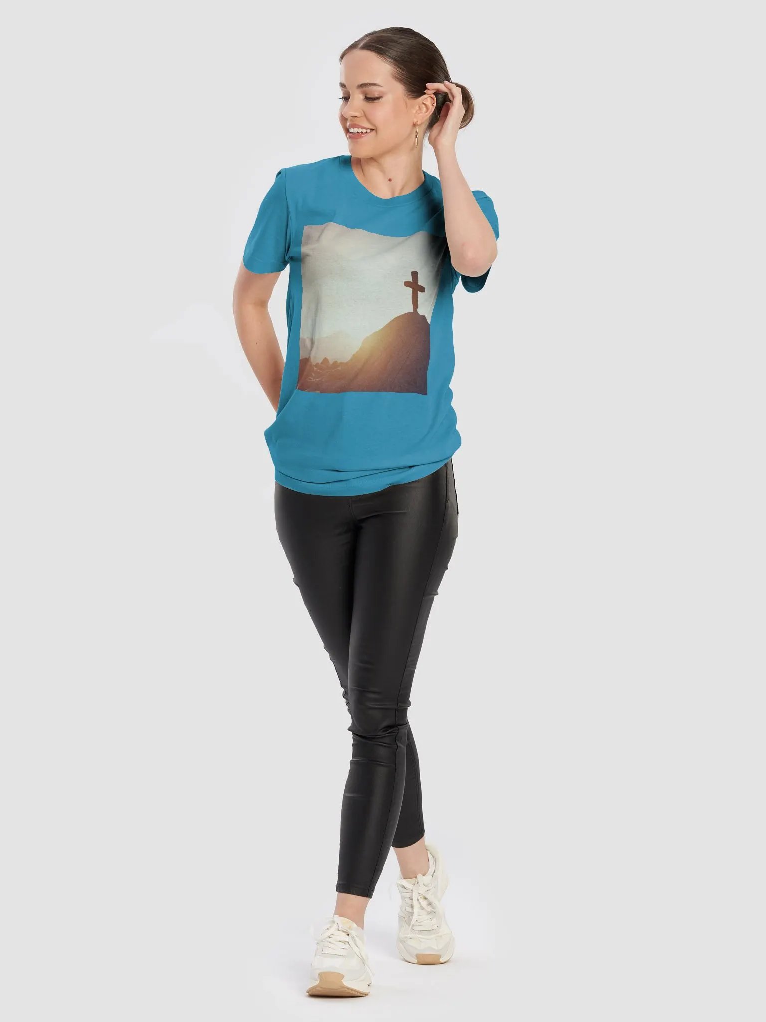A cross placed on top of a rocky hill, bathed in the warm glow of a sunrise or sunset t-shirt product image (4)